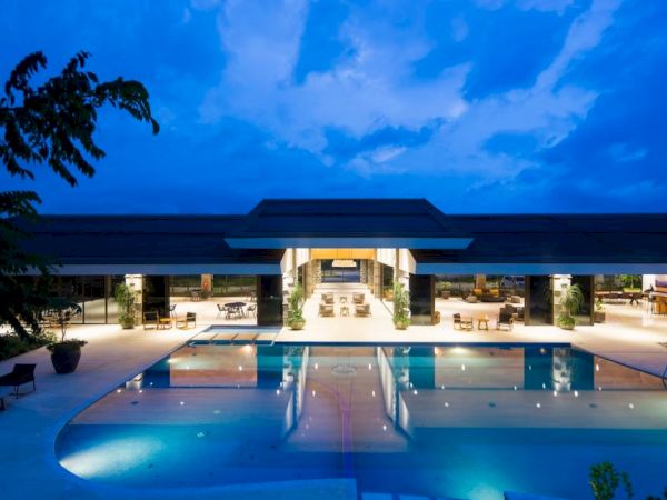 A modern, illuminated building with a large, reflecting pool in the foreground under a twilight sky.