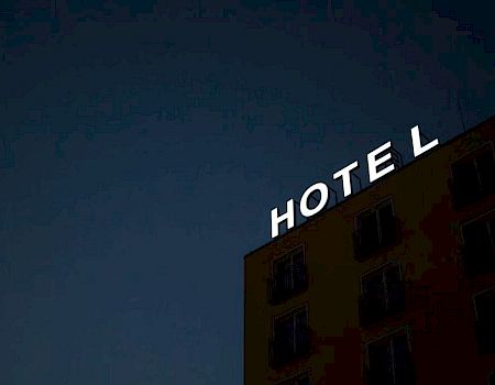 A building with a sign reading "HOTEL" against a dark sky; the "H" is not fully visible due to the angle of the photo.