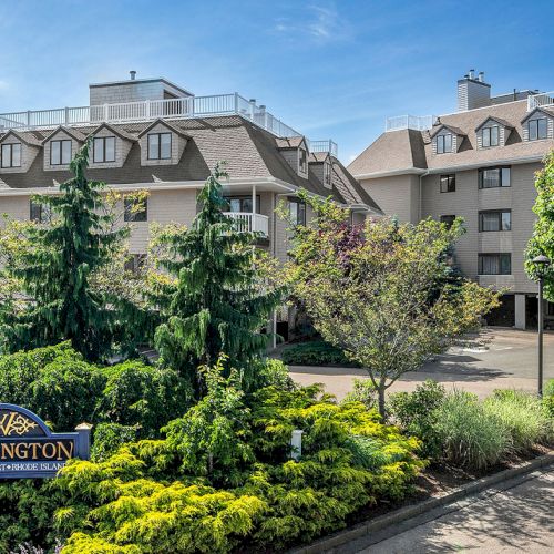 The image shows a residential building complex with well-maintained landscaping and a sign reading "Wellington" in the foreground.