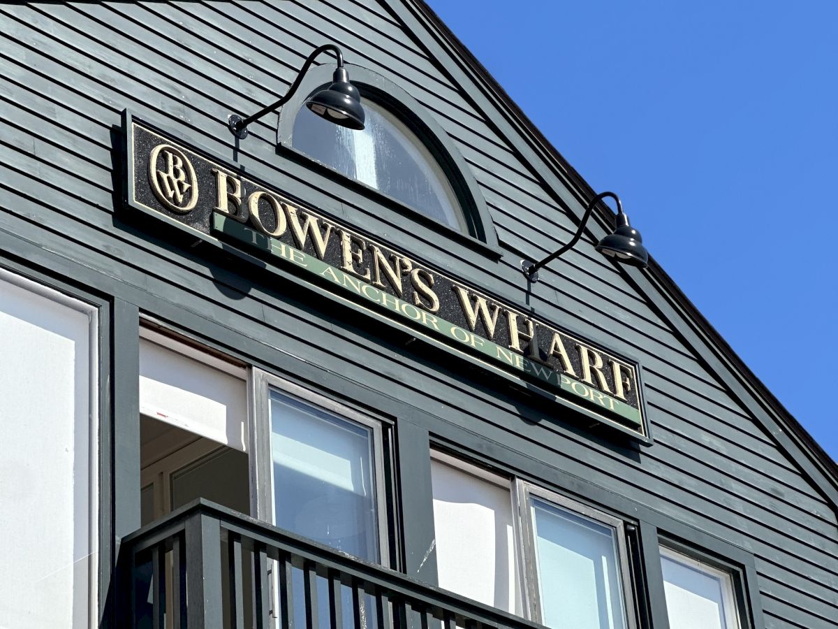 The image shows a building facade with a sign reading "Bowen's Wharf" under a clear blue sky.